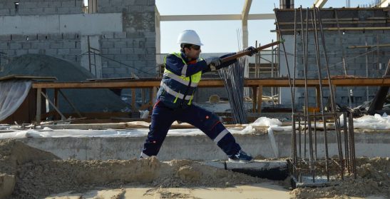 Outdoor worker bends metal on construction site