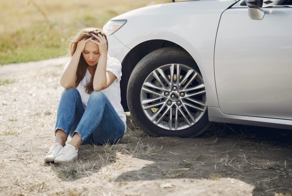 person sitting next to car after accident