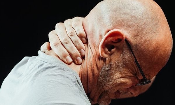 man holding back of neck in pain