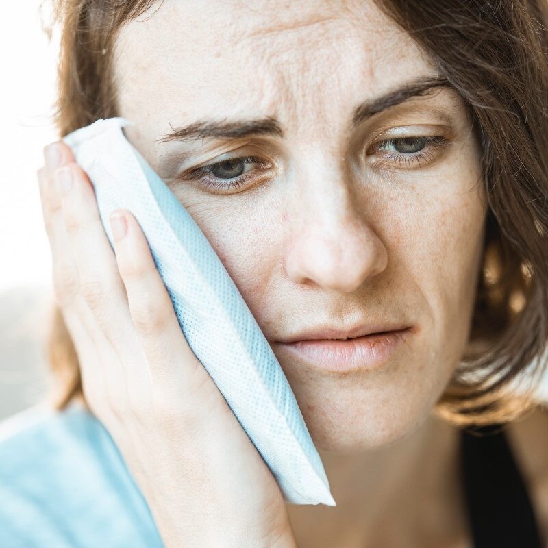 Person holding ice pack against their jaw