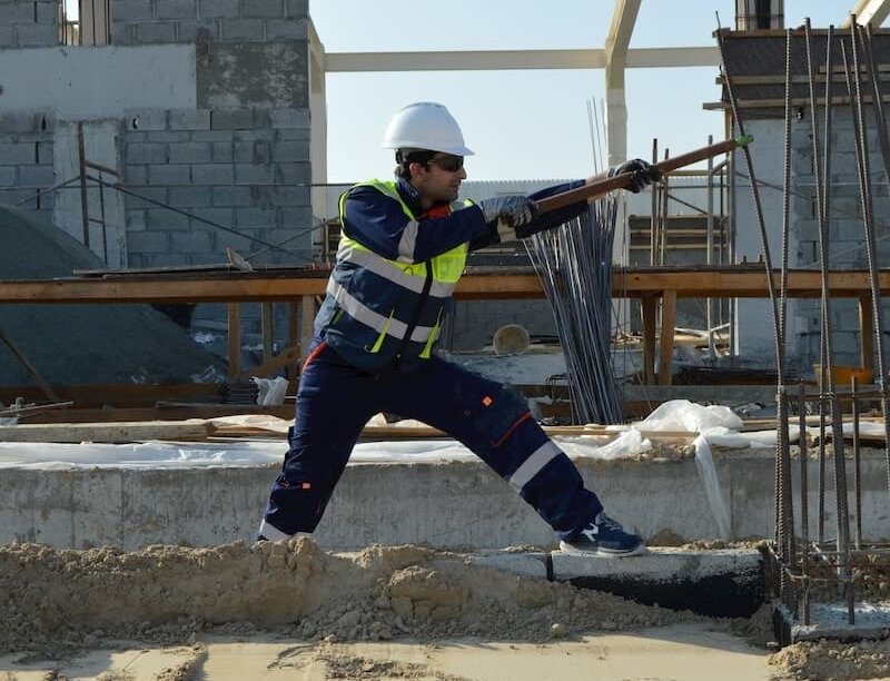 Outdoor worker bends metal on construction site